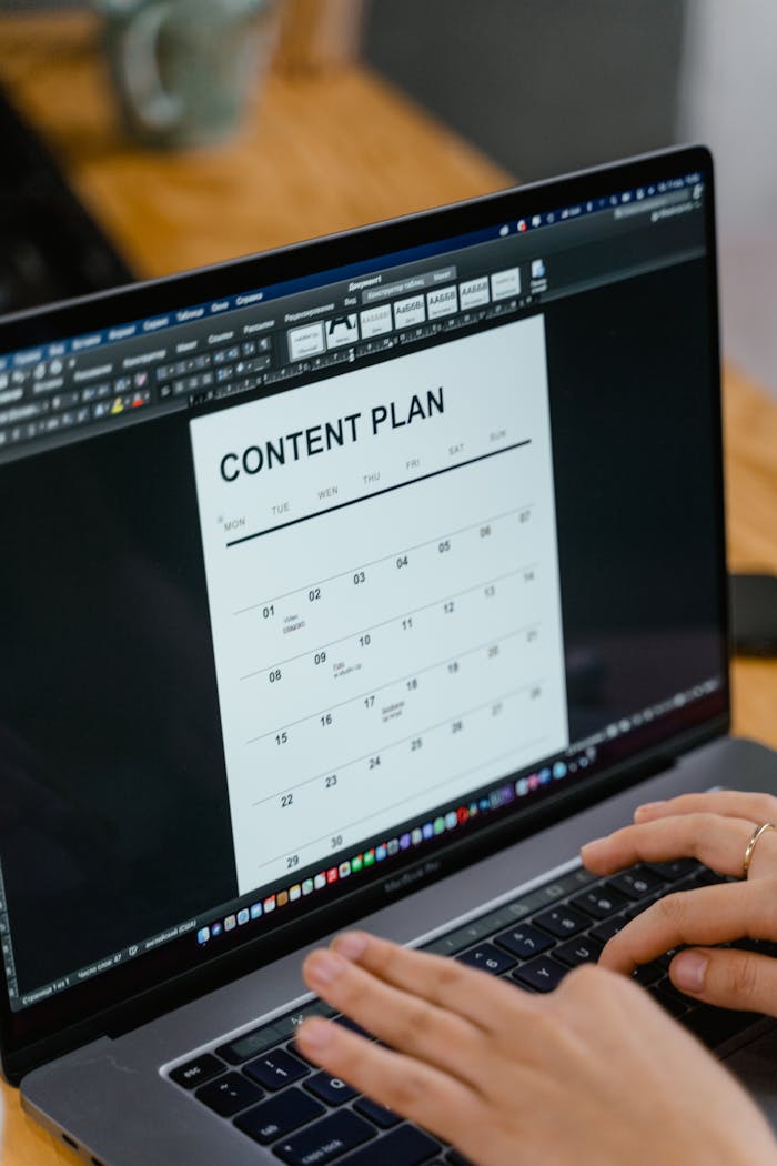 our-journey-02 Close-up of hands typing on a laptop displaying a content plan document, ideal for business or marketing content.